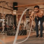 a shirtless man in a gym holding a rope
